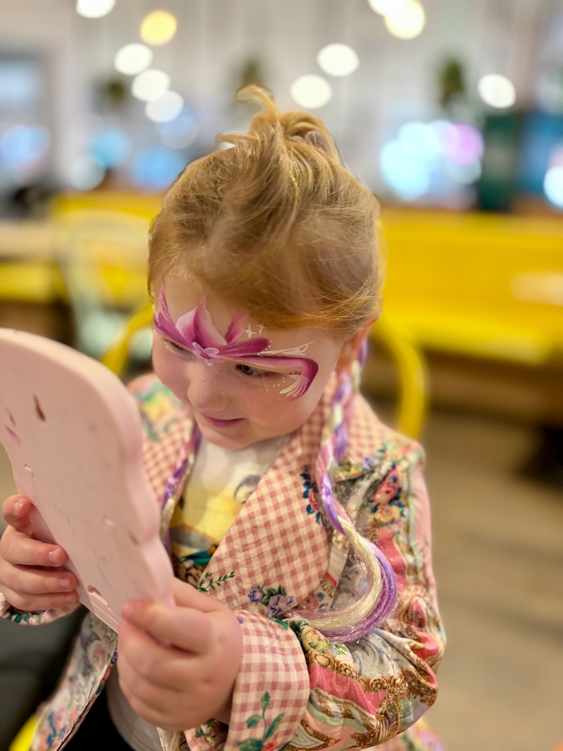 Toddler wearing fairy wings holding mirror